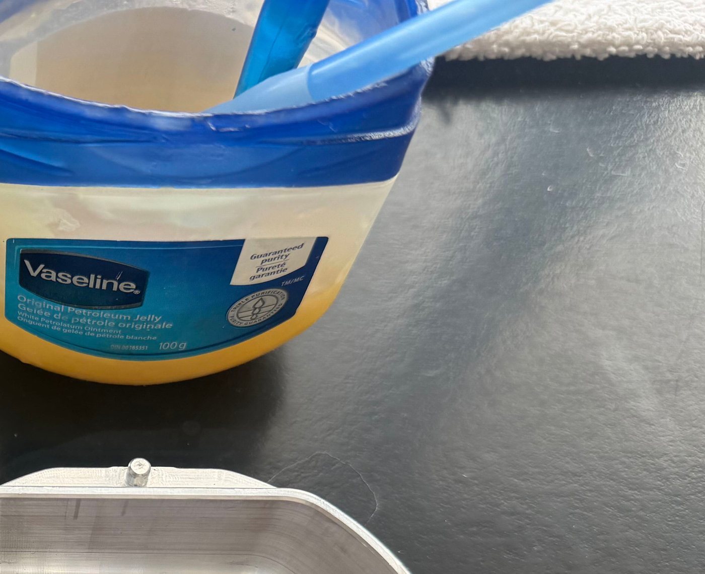 Open jar of Vaseline with a blue applicator beside a LabPilot flask