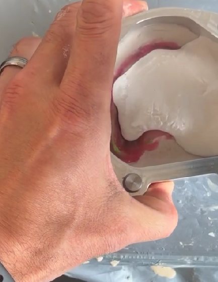 Hand holding the flask while plaster is added over the mid section